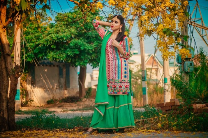 woman in green and red sari standing under green tree during daytime