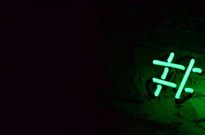 green neon light hashtag sign in a dark room.