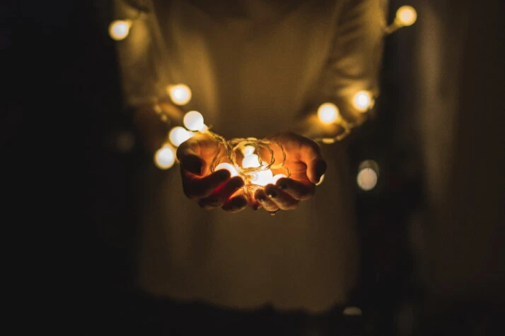 A person holding fairy lights at the palm of his hands.