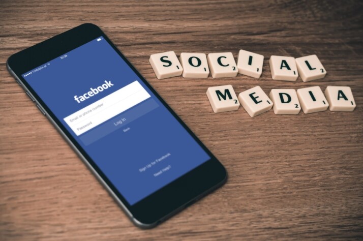 Android phone on wooden table near social media scrabble