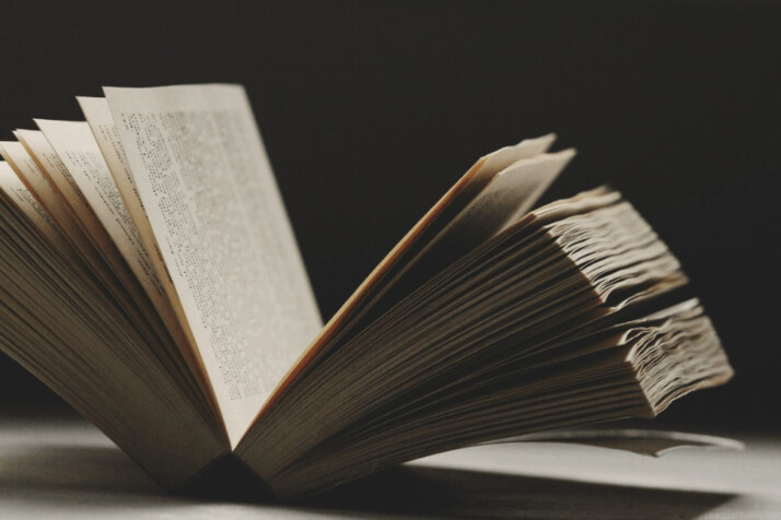 reflective photography on brown opened novel on white table