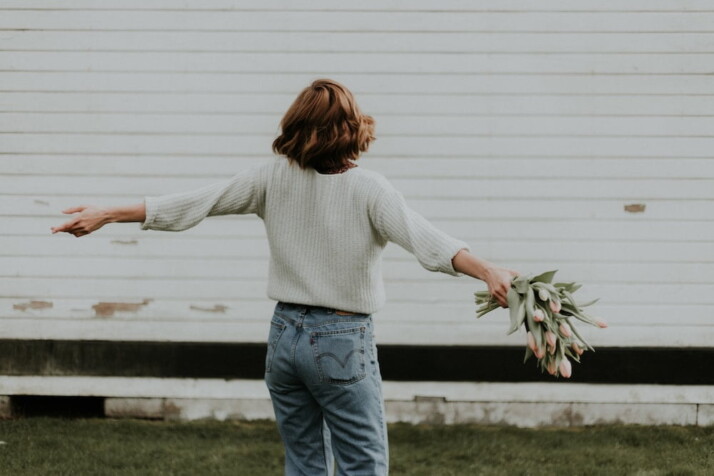 A picture of a woman holding pink petaled flowers