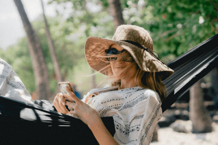A woman lying on black hammock while holding phone