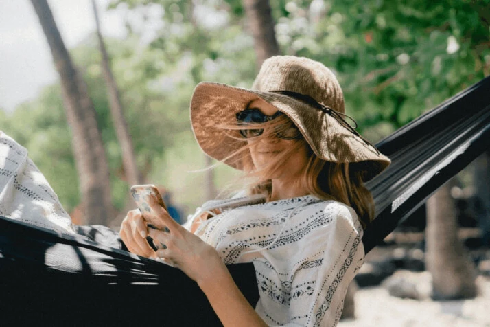 A woman lying on black hammock while holding phone