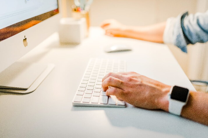 A person wearing a white watch, working on a computer.