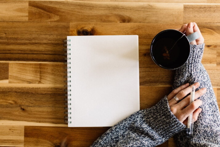 A blank page on a notebook, next to a cup of tea.