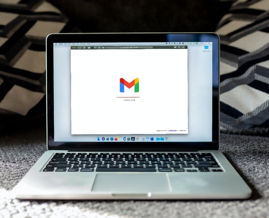 A laptop displaying the Gmail logo with a text that says