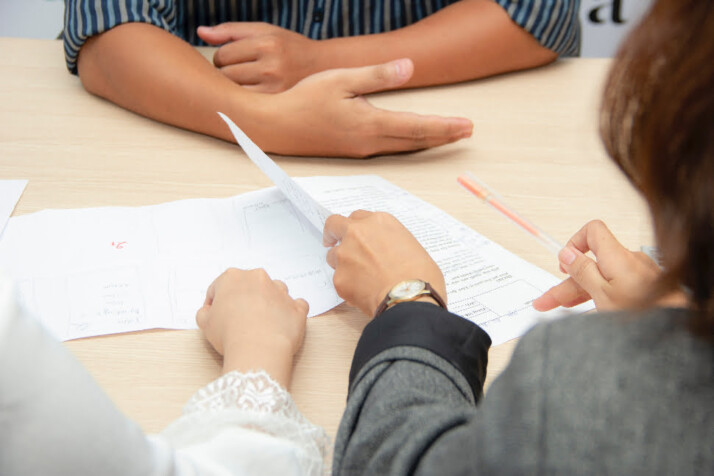 Two recruiters interviewing someone and looking at some papers.