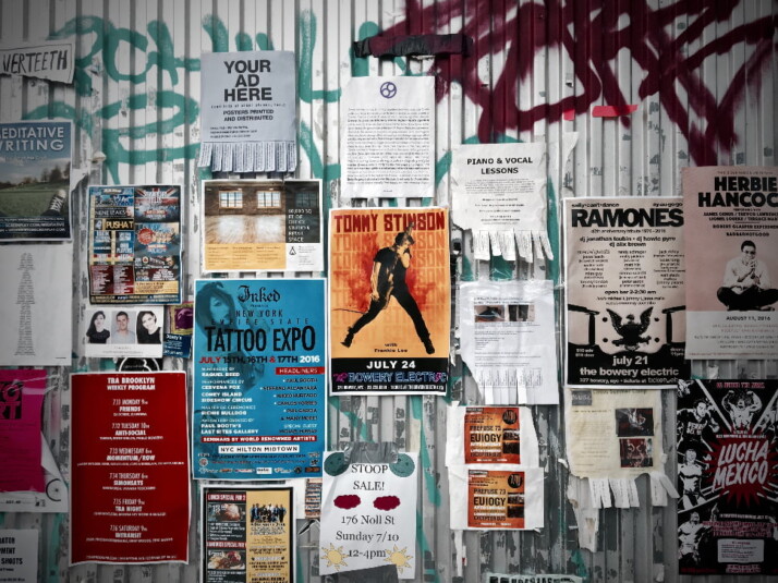 A variety of ad posters glues to a wall.