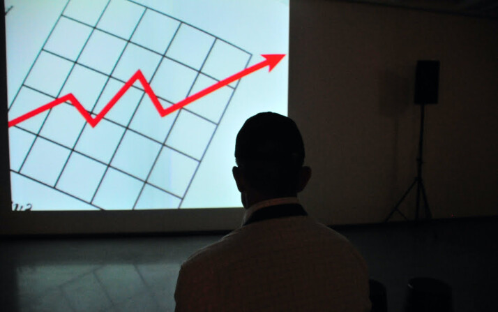 A person looking at a chart with a red arrow pointing upwards.
