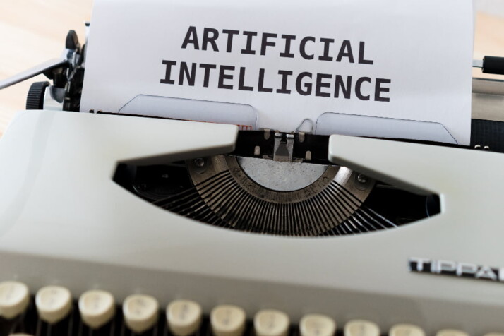 An Image of a typewriter with a piece of paper on top that has the word Artificial Intelligence typewritten on it