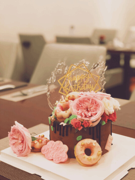 chocolate cake topped with roses and doughnuts in a fancy restaurant