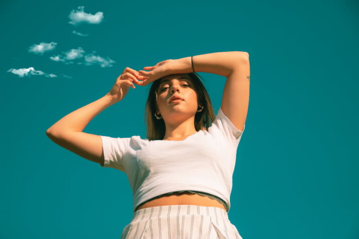 A girl posing for the camera with the sky as her background.