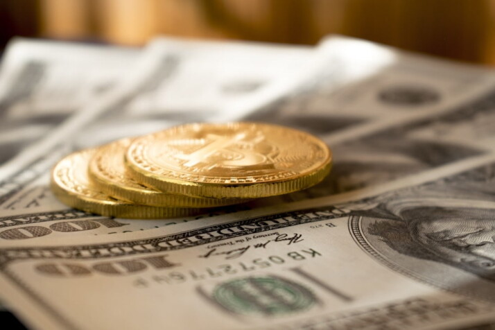 three round gold-colored coins on 100 US dollar banknotes