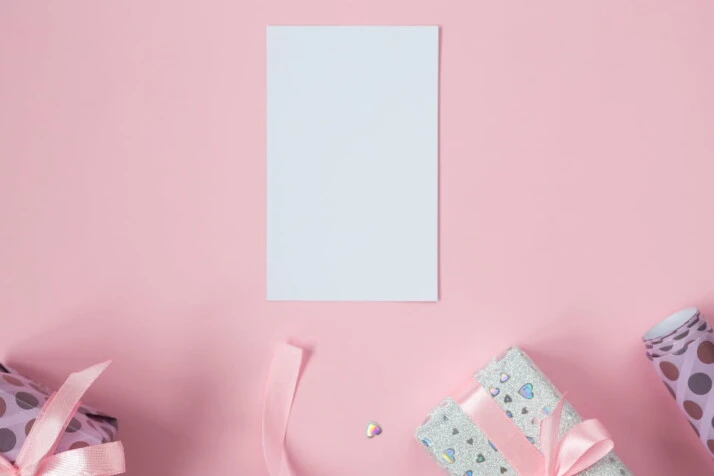 A blank piece of paper with a pink background, surrounded by presents.