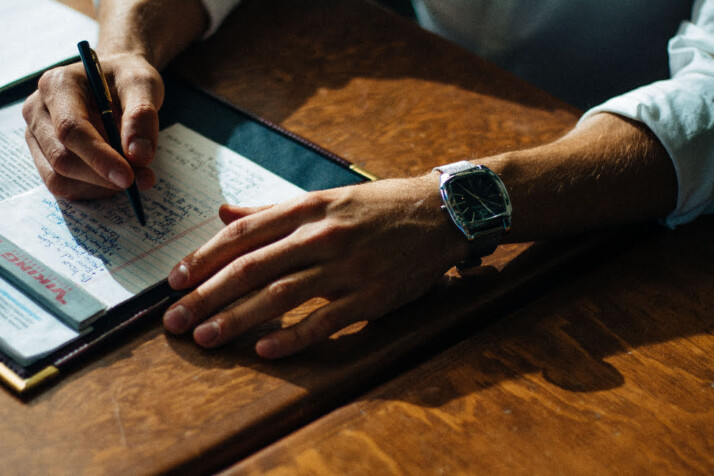 Man writes at a table.