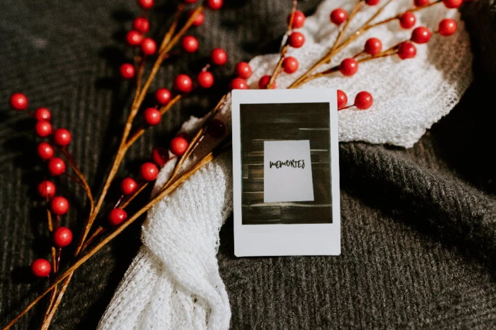 A polaroid photo with the word Memories placed next to a white scarf.