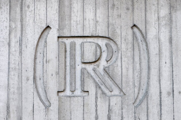 The letter R with parenthesis carved into a grey surface..