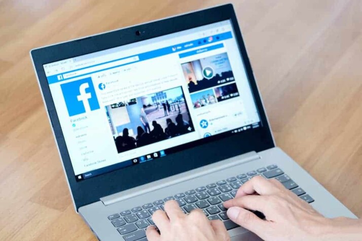 two hands on silver laptop keyboard placed on brown table