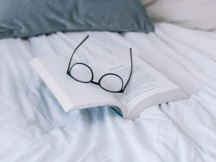 An open book with a pair of glasses on top of it.