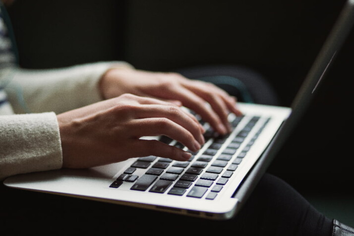 A person who's typing something on the laptop placed on their lap.