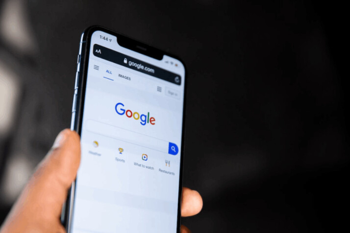 Person holding black android smartphone showing google's search bar