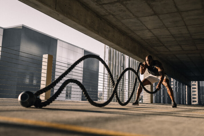 A man exercising using battle ropes in both hi