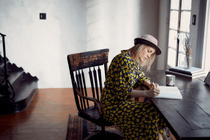 woman in yellow and black floral dress sitting on brown wooden chair