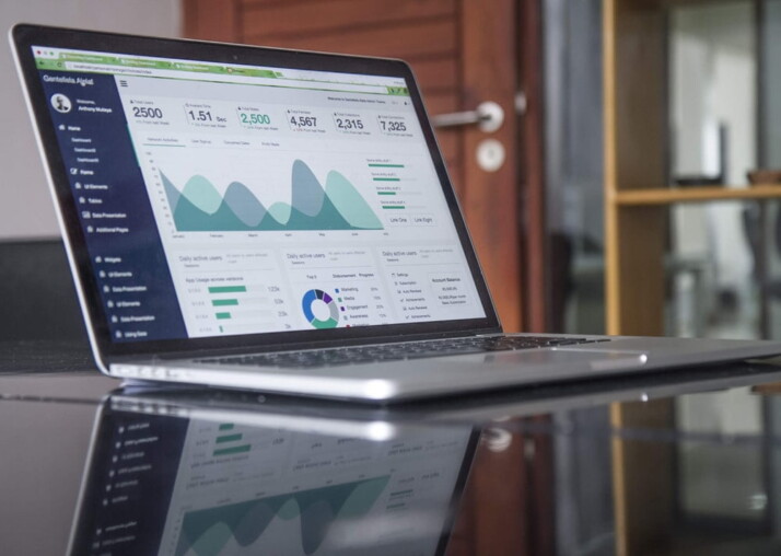 laptop computer on glass-top table displaying graphs and charts