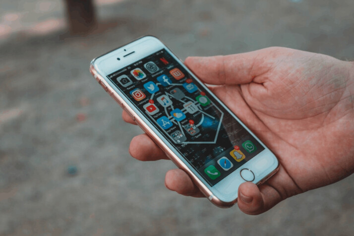 person holding white gold iPhone 6 displaying phone applications