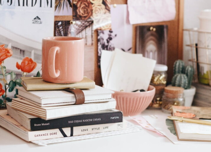 A pile of books on a table with a mug on top