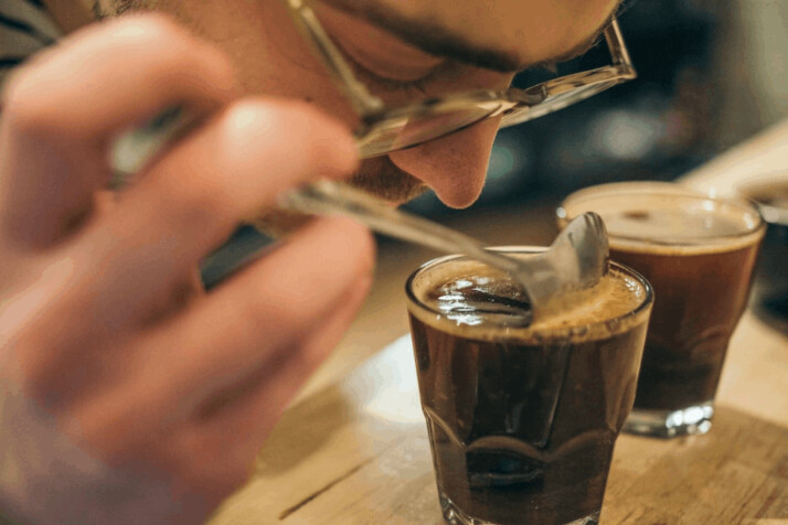 clear drinking glass filled with coffee on brown wooden surface