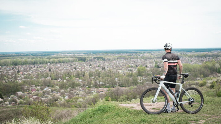 A biker standing next to his bike while staring at the country side.