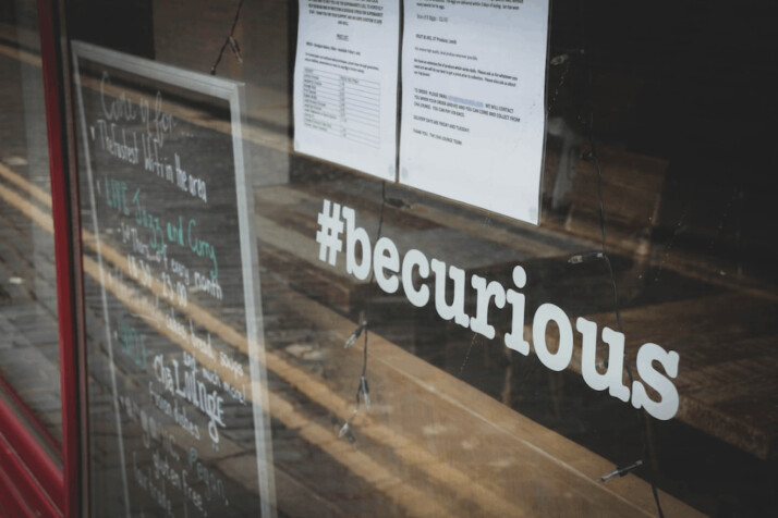 White printer paper on glass wall with a #becurious keyword