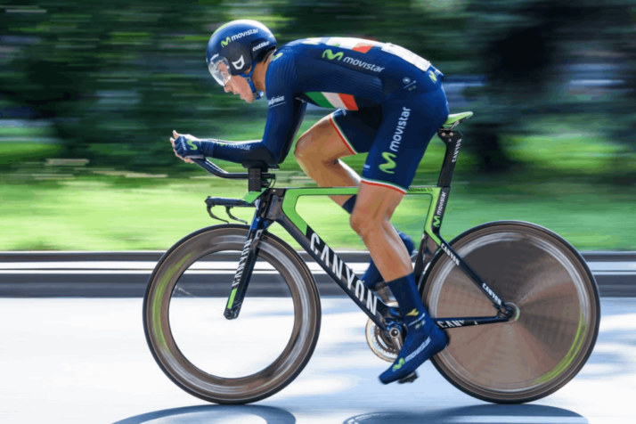 A man in a navy blue jersey is in a triathlon bike