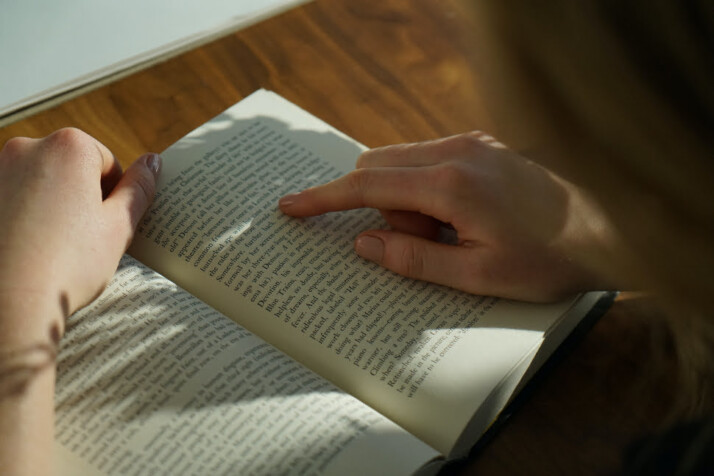 A person reading a book with his hands on the pages.