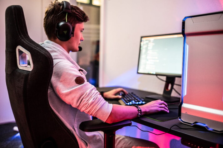 A guy sitting on a gaming chair working on a computer.