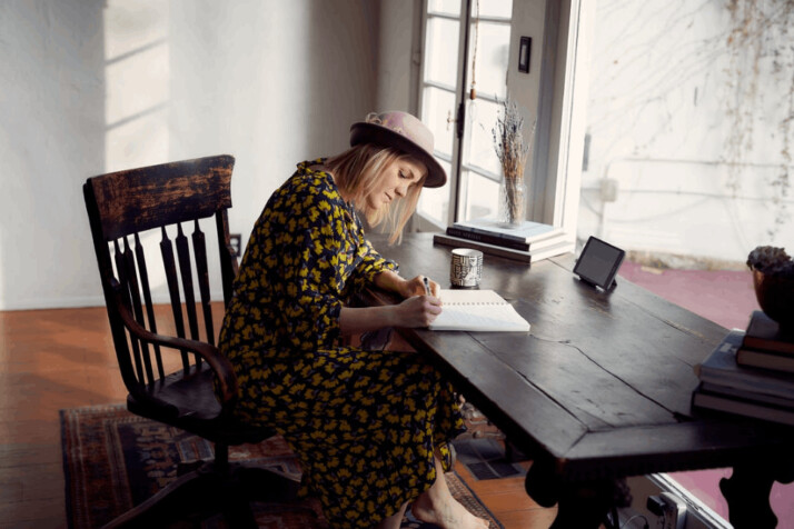 woman in yellow and black floral dress sitting on brown wooden chair