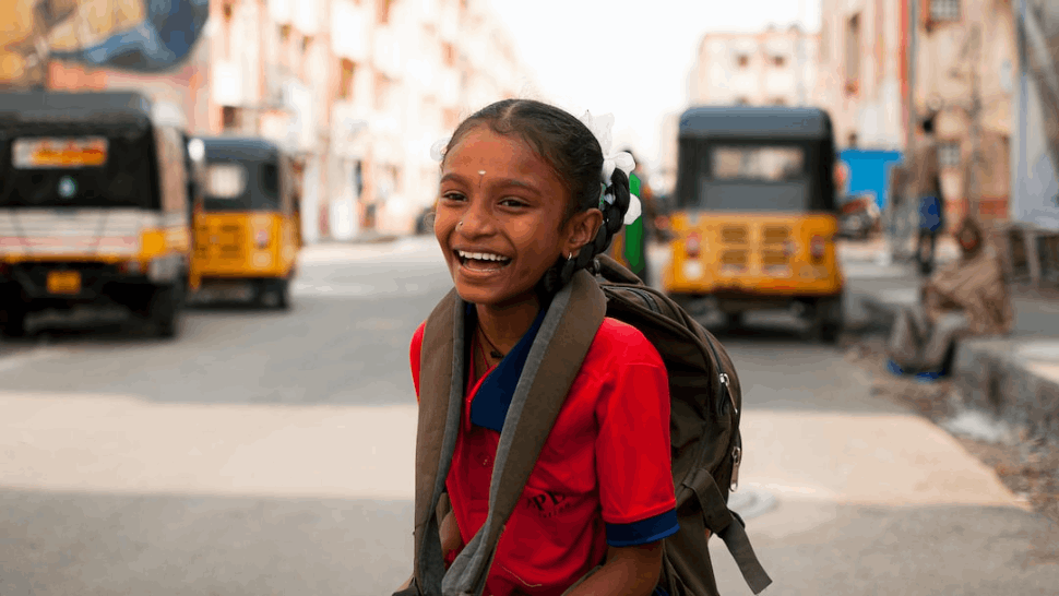 smiling girl in red and gray jacket wearing blue headphones