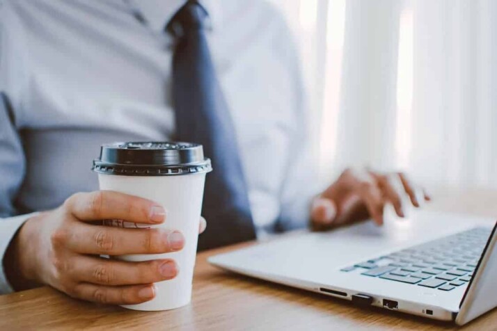 person wearing blue shirt and tie, using silver laptop 