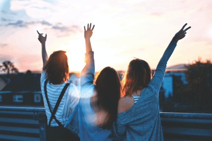 A photo of three women lifting there hands in the air