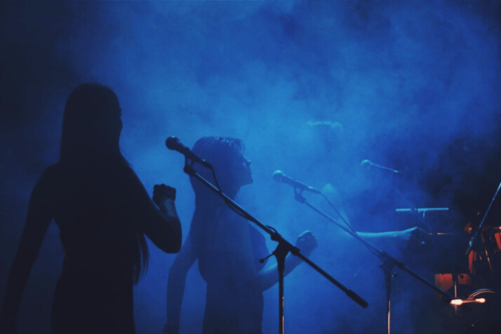 silhouette photography of three women standing in front of microphone stands