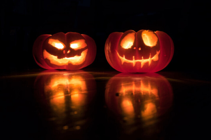 two jack o lanterns in a dark room with lights inside.