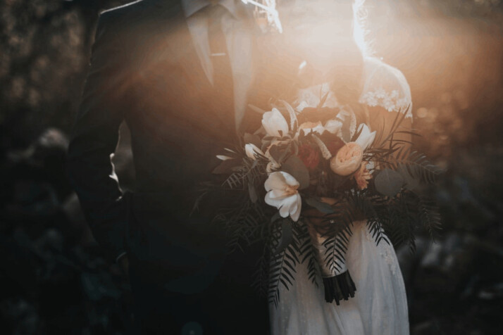 A groom beside his bride holding a bouquet of flowers