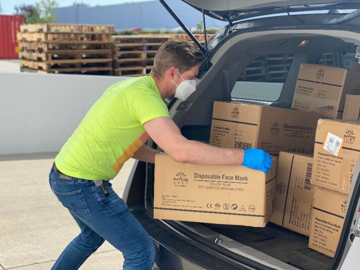 A person hauling big boxes from the back of a car.