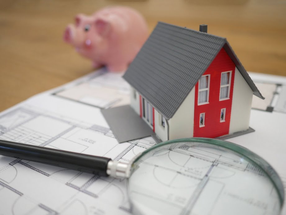 A miniature model of a house with a magnifying glass next to it.