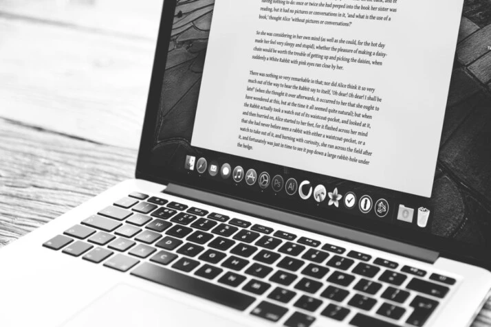 black and white photo of a silver MacBook showing a word processing application