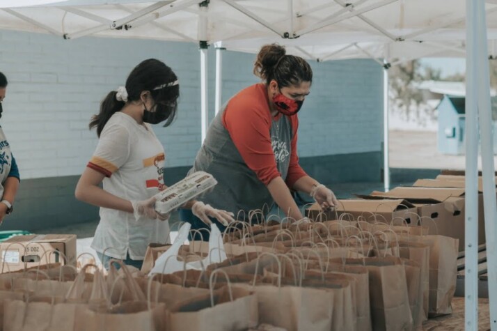 Two women volunteers who are putting things in paper bags.