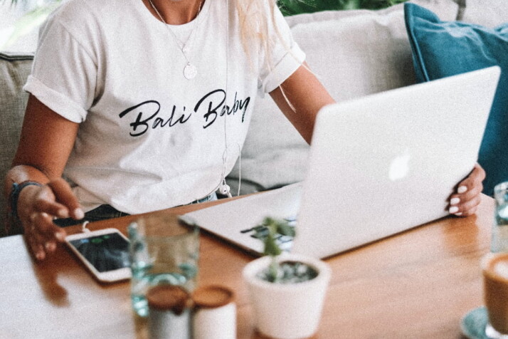 A person wearing a white shirt working on their laptop.