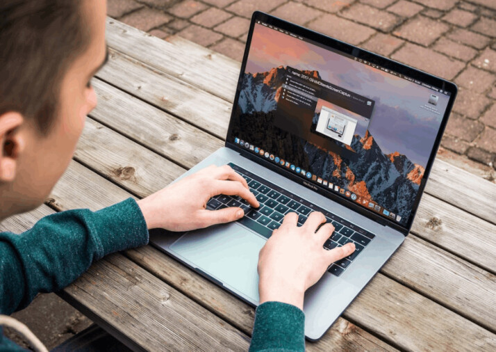 A person using MacBook and typing on the keyboard